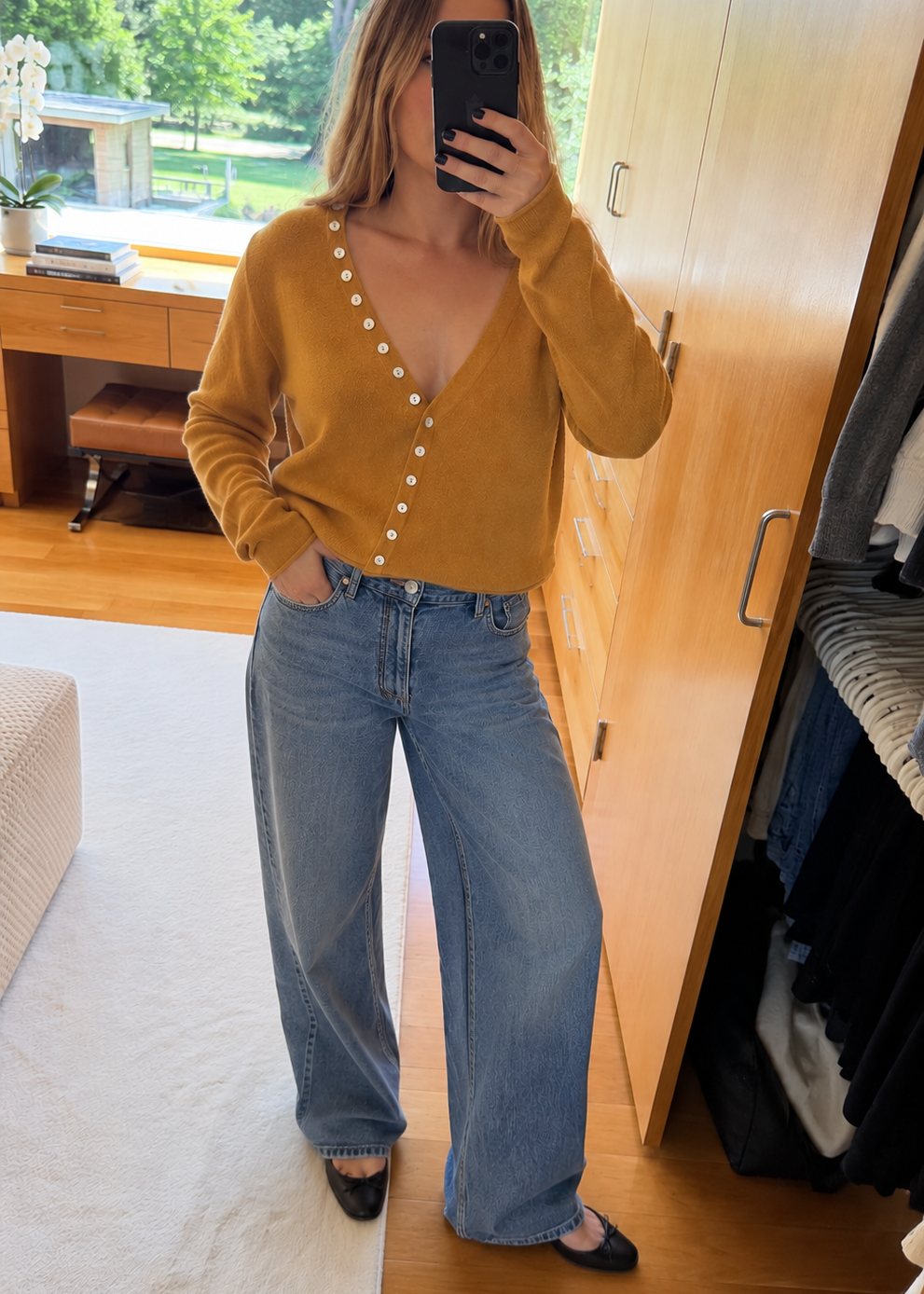 tumeric orange cashmere sweater with pearl buttons and model wearing jeans and flats